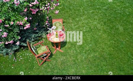 Dekorierter Tisch mit Brot, Erdbeeren und Früchten im wunderschönen Rosengarten im Sommer, Blick von oben auf romantische Datteltische für zwei Personen Stockfoto