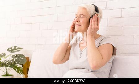 Frau, die Musik hört, während sie sich im Bett entspannt Stockfoto