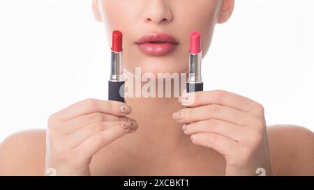 Frau, die zwei Lippenstifte hält, eine Wahl treffen Stockfoto