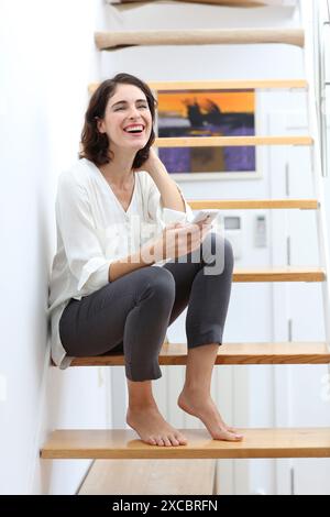 Frau sitzt auf der Treppe und mit Smartphone Stockfoto