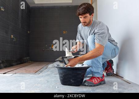 Maurer, der Fliesenkleber zum Fliesen aufträgt. Bau eines Wohngebäudes. Donostia. San Sebastian. Gipuzkoa. Baskenland. Spanien. Stockfoto