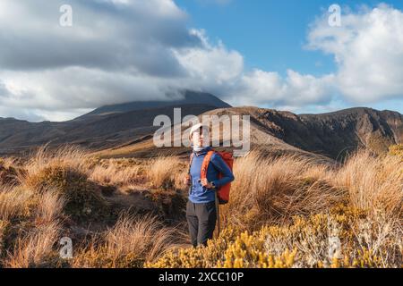 Schöne asiatische Reisende Frau Wandern und genießen mit vulkanischen Bergen und goldenen Wiesen in Tongariro Alpin Crossing Track am sonnigen Tag in Nord I Stockfoto