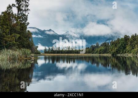 Landschaft des Lake Matheson Gletschersees mit Gebirgszügen und nebeliger Reflexion in Südwestland, Neuseeland Stockfoto