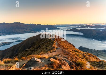 Atemberaubende Landschaft mit Sonnenaufgang über dem Gipfel des Roys Peak und dem nebligen Berg über dem Lake Wanaka im Herbst in Neuseeland Stockfoto