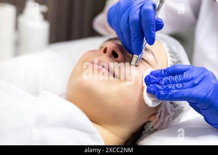 Nahaufnahme eines Kosmetikers, der das Verfahren Mikrodermabrasion der Gesichtshaut einer schönen, jungen Frau in einem Schönheits-Spa-Salon macht. Stockfoto