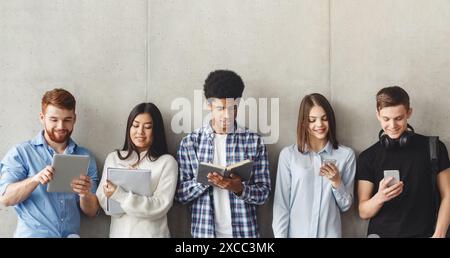 Diverse Studenten mit Bücher stehen in der Nähe der graue Wand Stockfoto