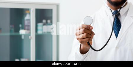 Männlicher Arzt hören mit Stethoskop über hellen Hintergrund Stockfoto