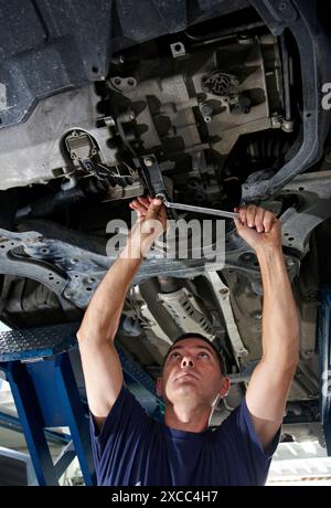 Arbeiter mit Ringschlüssel in Autowerkstatt Stockfoto