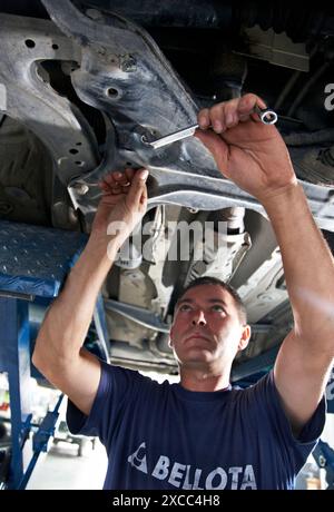 Arbeiter mit Ringschlüssel in Autowerkstatt Stockfoto