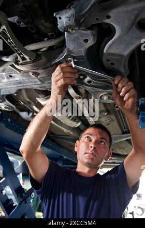 Arbeiter mit Ringschlüssel in Autowerkstatt Stockfoto