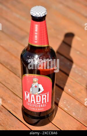 Madri außergewöhnliche spanische Cerveza Bier Red Label Flasche im Freien mit einem Schatten auf Holztisch Stockfoto