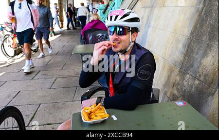 Brighton UK 16. Juni 2024 - dieser Radfahrer genießt eine Schüssel Chips an der Küste von Brighton, nachdem er heute die 54 km lange British Heart Foundation London to Brighton Bike Ride absolviert hat, die jedes Jahr Tausende von Fahrern anzieht: Credit Simon Dack / Alamy Live News Stockfoto