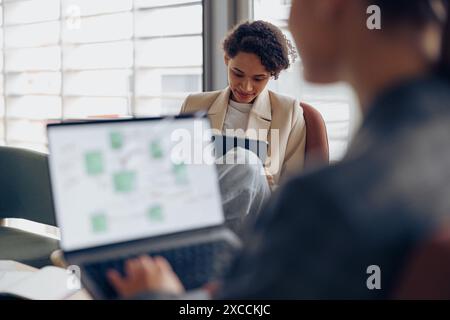 Fokussierte junge Geschäftsfrauen verwenden Gadgets, während sie im Coworking arbeiten. Konzept der Fernarbeit Stockfoto