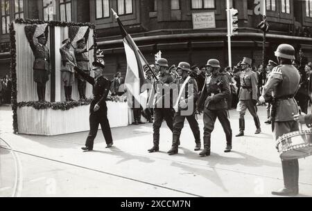 Eine Parade der niederländischen Freiwilligenlegion der Waffen-SS auf der Groten Marktstraße in den Haag im Jahr 1941. Auf dem Bahnsteig befinden sich General Friedrich Christiansen (links), Generalleutnant Hendrik Seyffardt (Mitte) und SS-Obergruppenführer Hanns Albin Rauter (rechts). Seyffaardt trägt seine Uniform der niederländischen Armee (was ein Akt des Verrats war). 1943 wurde er vom niederländischen Widerstand ermordet. Stockfoto