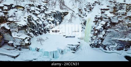 Wunderschöne schneebedeckte felsige Landschaft mit gefrorenen Wasserfällen in der Abiskojåkka-Schlucht im Abisko-Nationalpark in Nordschweden. Stockfoto