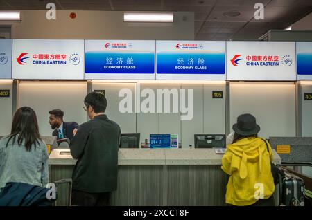 Chinesische Passagiere stehen in der Warteschlange, um für einen Flug von China Eastern nach Shanghai vom Flughafen London Gatwick, Großbritannien, einzuchecken. Stockfoto