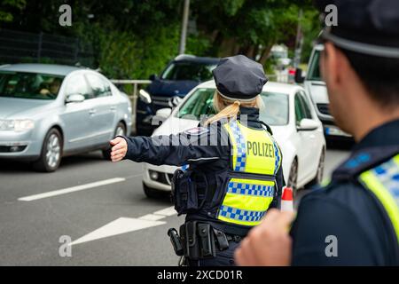 Hamburg, Deutschland. Juni 2024. Eine Polizistin zeigt Autos in der Nähe des Volksparkstadions an einer von der Polizei gesperrten Zufahrtsstraße. Quelle: Jonas Walzberg/dpa/Alamy Live News Stockfoto