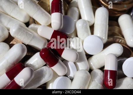 Weiße und rote Kapselpillen wurden über mehrere Münzen verteilt. Stockfoto
