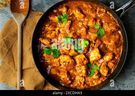 Ein Schuss Hühnercurry in einer Pfanne mit einem Holzlöffel und Serviette auf der Küchenzeile Stockfoto