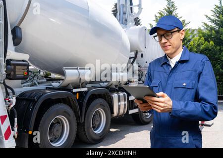 Mitarbeiter mit digitalem Tablet neben Lkw-Betonpumpe mit Mischer. Stockfoto