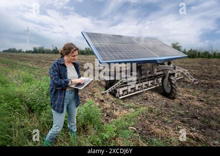 Der Landwirt steuert autonome Landmaschinen, die mit Solarenergie betrieben werden. Stockfoto