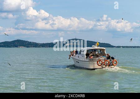 Wassertaxi mit Touristen auf dem Balaton mit dem Hügel Fonyód im Hintergrund. Badacsony, Ungarn, August 31. 2023. Stockfoto