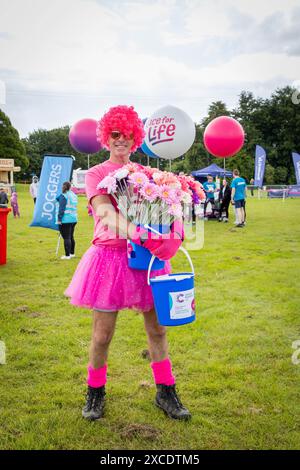 Warrington, Cheshire, Großbritannien. Juni 2024. Das jährlich stattfindende 10K-Rennen um das Leben zur Unterstützung von Cancer Research UK fand im Victoria Park, Warrington, statt. Es geht darum, rosa zu tragen und Mittel für die Krebsforschung zu sammeln. Freiwillige halfen der Sache, indem sie Merchandise Credit: John Hopkins/Alamy Live News verkauften Stockfoto