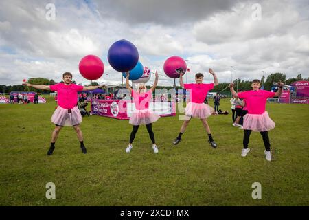 Warrington, Cheshire, Großbritannien. Juni 2024. Das jährlich stattfindende 10K-Rennen um das Leben zur Unterstützung von Cancer Research UK fand im Victoria Park, Warrington, statt. Lokale Fitnesslehrer machen vor dem Rennen Star Jumps Credit: John Hopkins/Alamy Live News Stockfoto