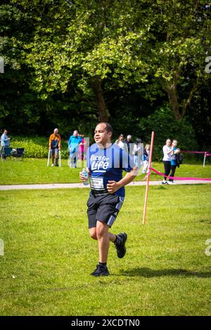 Warrington, Cheshire, Großbritannien. Juni 2024. Das jährlich stattfindende 10K-Rennen um das Leben zur Unterstützung von Cancer Research UK fand im Victoria Park, Warrington, statt. Reifer Mann in Race for Life Trikot geht auf den Kurs. Quelle: John Hopkins/Alamy Live News Stockfoto