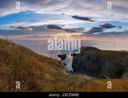 Der Himmel beleuchtet durch steigende Sonne und Seelandschaft von felsigen Klippen. Stockfoto