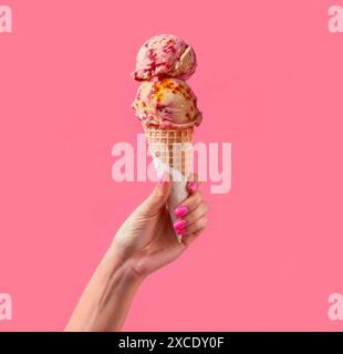 Köstliches Eis, das von der Frauenhand auf rosafarbenem Hintergrund gehalten wird Stockfoto