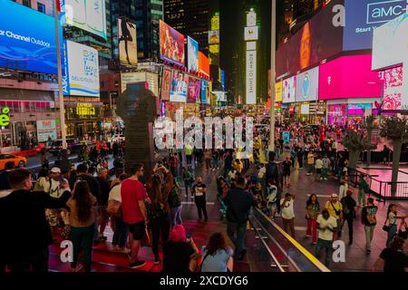 Atemberaubender Blick bei Nacht von den Red Steps of Times Square in Manhattan, bei dem die Leute durch die hell beleuchteten Plakate auf dem Wolkenkratzer spazieren gehen Stockfoto
