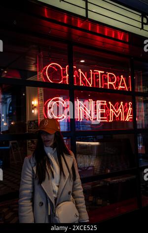 01.04.2023, London, junge Frau mit Mütze posiert neben den berühmten roten Buchstaben des Central Cinema. Das Bild fängt einen lässigen und urbanen Moment ein, Hi Stockfoto