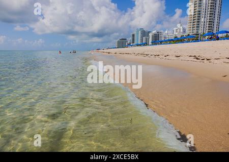 Wolkenkratzer erstrecken sich entlang der Küste von Miami Beach und verschmelzen mit ausgestatteten Sandstränden mit Sonnenschirmen und Liegestühlen. Stockfoto