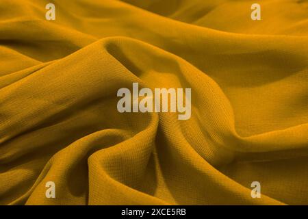 Eine Nahaufnahme aus gelbem Stoff mit weichen Falten und Textur Stockfoto