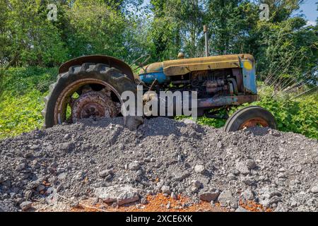 Nahaufnahme eines heruntergekommenen landwirtschaftlichen Traktors. In einem Zustand der Verwerfung wird es auf einem Feld auf einem harten Kern geparkt. Stockfoto