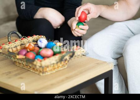 ostereierklopfen, Mutter und Sohn Eierklopfen neben Korb mit ostereiern, selektiver Fokus, Nahaufnahme der Hände Eierklopfen Stockfoto