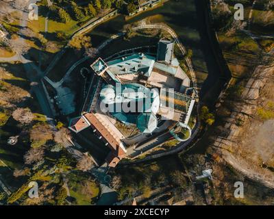 Von oben nach unten auf Bojnicky Zamok in der Abendsonne, berühmte Burg in Bojnice, Slowakei. Über dem Kopf mit mittelalterlichen blauen Dächern und Baumspitzen, Straße um die Festung und langen Schatten des Palastes Stockfoto