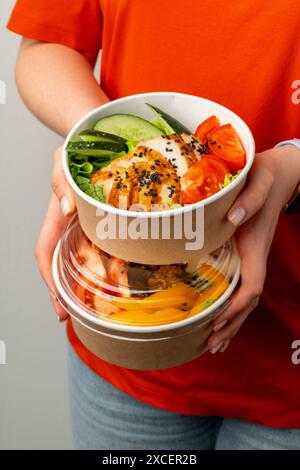 Weibliche Hände, die zwei Poke-Schüsseln mit Hühnchen und Gemüse halten Stockfoto