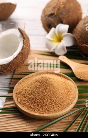 Kokoszucker, Palmblätter, Früchte und Bambusmatte auf rustikalem Holztisch, Nahaufnahme Stockfoto