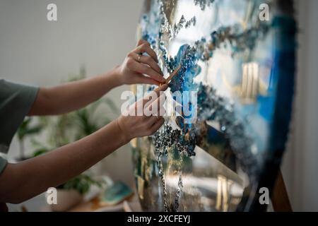 Anmutige, behutsame Arme einer Künstlerin, die Arbeiten an Epoxidharz-Projekt, Uhr, Uhr. Stockfoto