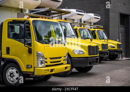 Sattelauflieger für mittelschwere Transportfahrzeuge mit Day Cab und Kühlkoffer für örtliche Frachten, die in Reihe auf der städtischen Straße stehen Stockfoto