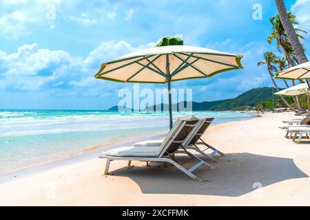 Sonnenliegen unter tropischen Palmen am Strand auf Phu Quoc Insel, Vietnam. Das Lächeln des Strands Stockfoto