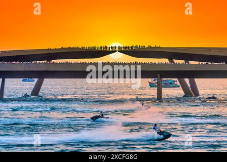 Künstler, die Jetski und Flyboard auf dem Wasser in der Stadt bei Sonnenuntergang aufführen, ziehen viele Touristen in Phu Quoc, Vietnam, an Stockfoto