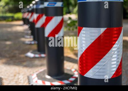 Eine Reihe schwarz-weiß gestreifter Stangen mit roten und weißen Streifen. Die Stangen sind in einer Reihe angeordnet und auf dem Boden platziert Stockfoto