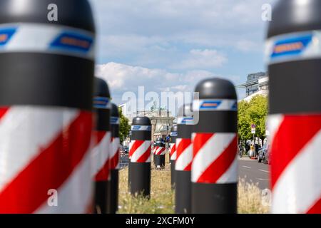 Eine Reihe rot-weiß gestreifter Stangen stehen auf einer Straße. Hier ist eine Reihe rot-weiß gestreifter Barrieren auf der Straße. Das Brandenburger Tor ist V Stockfoto