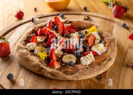 Gourmet-Dessert-Pizza auf Holztisch, umgeben von Zutaten Stockfoto