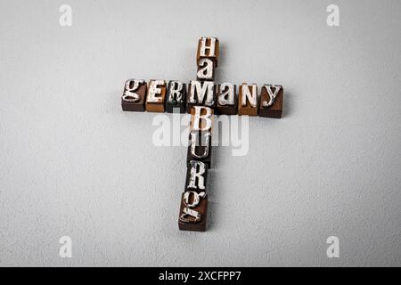 DEUTSCHLAND HAMBURG. Alphabetblöcke, Kreuzworträtsel auf grauem, strukturiertem Hintergrund. Stockfoto