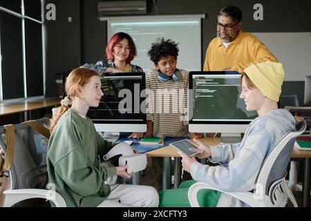 Teenager, die ein digitales Tablet und ein VR-Headset während des modernen Computerwissenschaftsunterrichts in der Schule verwenden Stockfoto