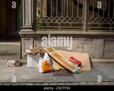 Cremona, Italien - 10. Juni 2024 Kartonkisten und Plastikmüllsäcke liegen auf einem Bürgersteig in der Straße Stockfoto